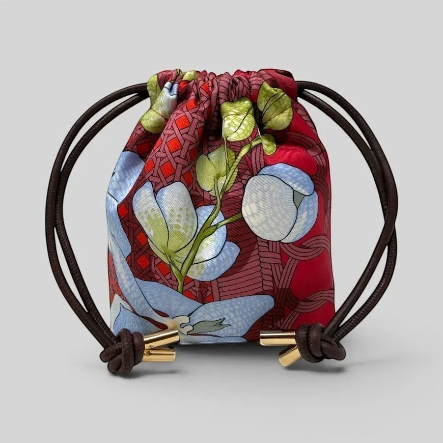 Prettysac Souvenirs D'Asie drawstring pouch with floral print in red, blue, white, and green. Features gold hardware.