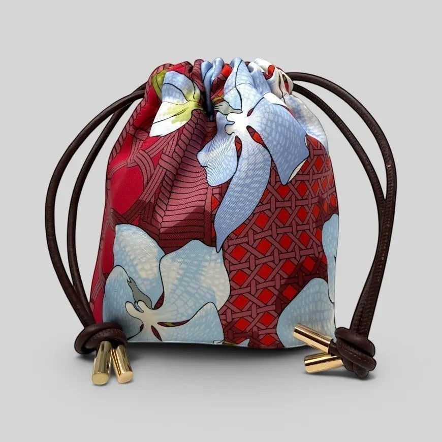 Prettysac Souvenirs D'Asie drawstring pouch with floral print in blue, white, crimson, and red. Features geometric patterns and gold hardware.