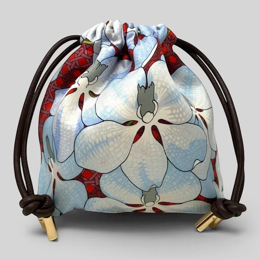 Prettysac Souvenirs D'Asie drawstring pouch with floral print in blue, white, and crimson. Features geometric pattern and gold hardware.