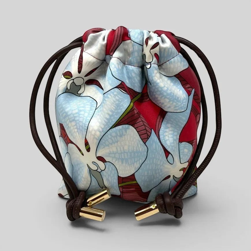 Prettysac Souvenirs D'Asie drawstring pouch with floral print in blue, white, and crimson. Features dark brown cords and gold hardware.