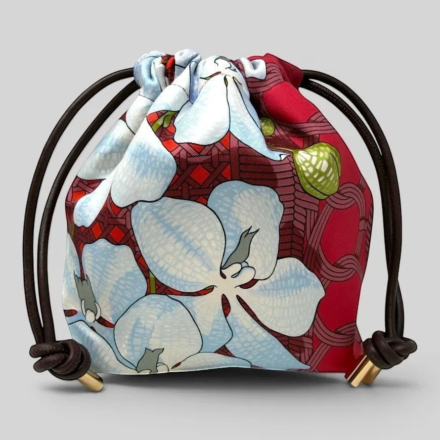 Prettysac Souvenirs D'Asie drawstring pouch with floral print in blue, white, crimson, and geometric patterns. Features dark brown cords and gold hardware.