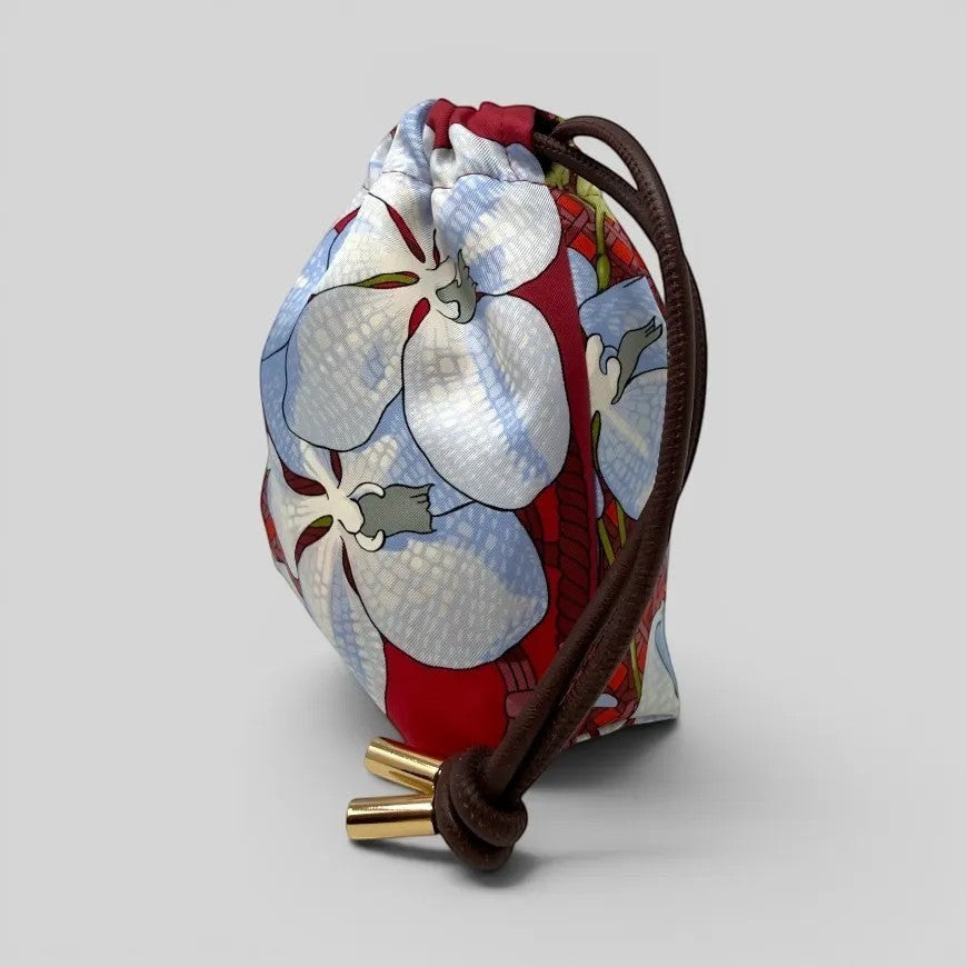 Prettysac Souvenirs D'Asie floral print drawstring pouch with blue, white, and crimson orchids. Features gold-tipped cords.