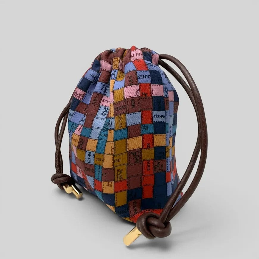 Prettysac artisanal patchwork pouch with dark brown leather drawstring and gold-tone hardware. Features iconic motifs and rich colours.